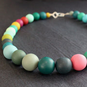 close up detail of a Claire Lloyd necklace of round beads in greens, pinks, blues and yellow 