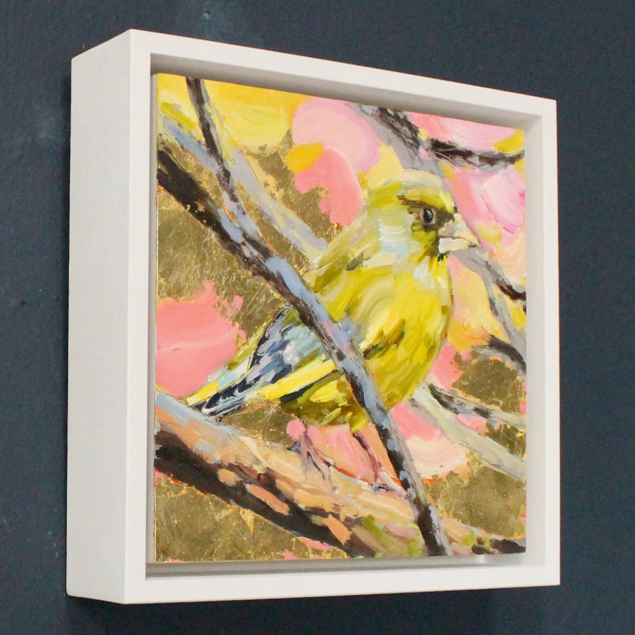 a Jill Hudson painting of a greenfinch on a branch with a pink, yellow and gold background.