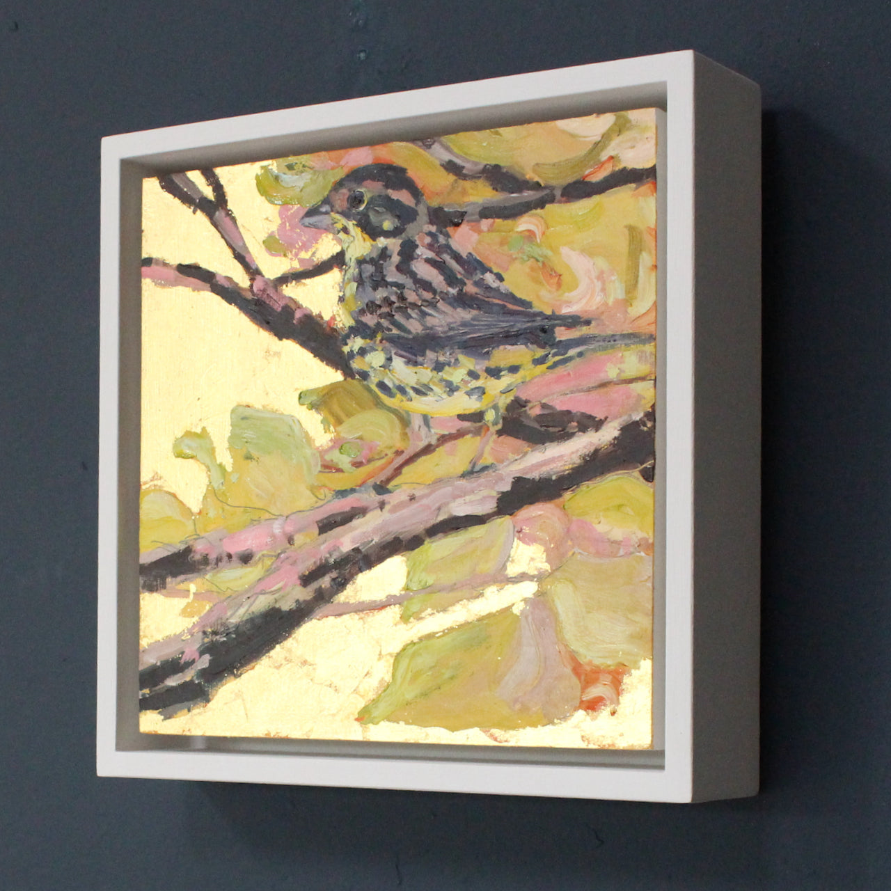 a framed Jill Hudson painting of a yellow hammer bird on a branch amid leaves in shades of yellow, gold and pink