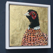 a framed Jill Hudson painting of a pheasant on a gold background