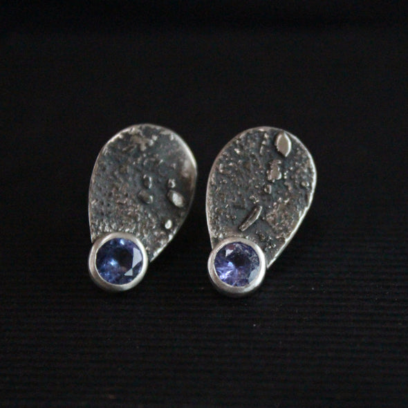 a pair of pair of Carin Lindberg textured silver earrings teardrop shape with silver encased small purple stone.
