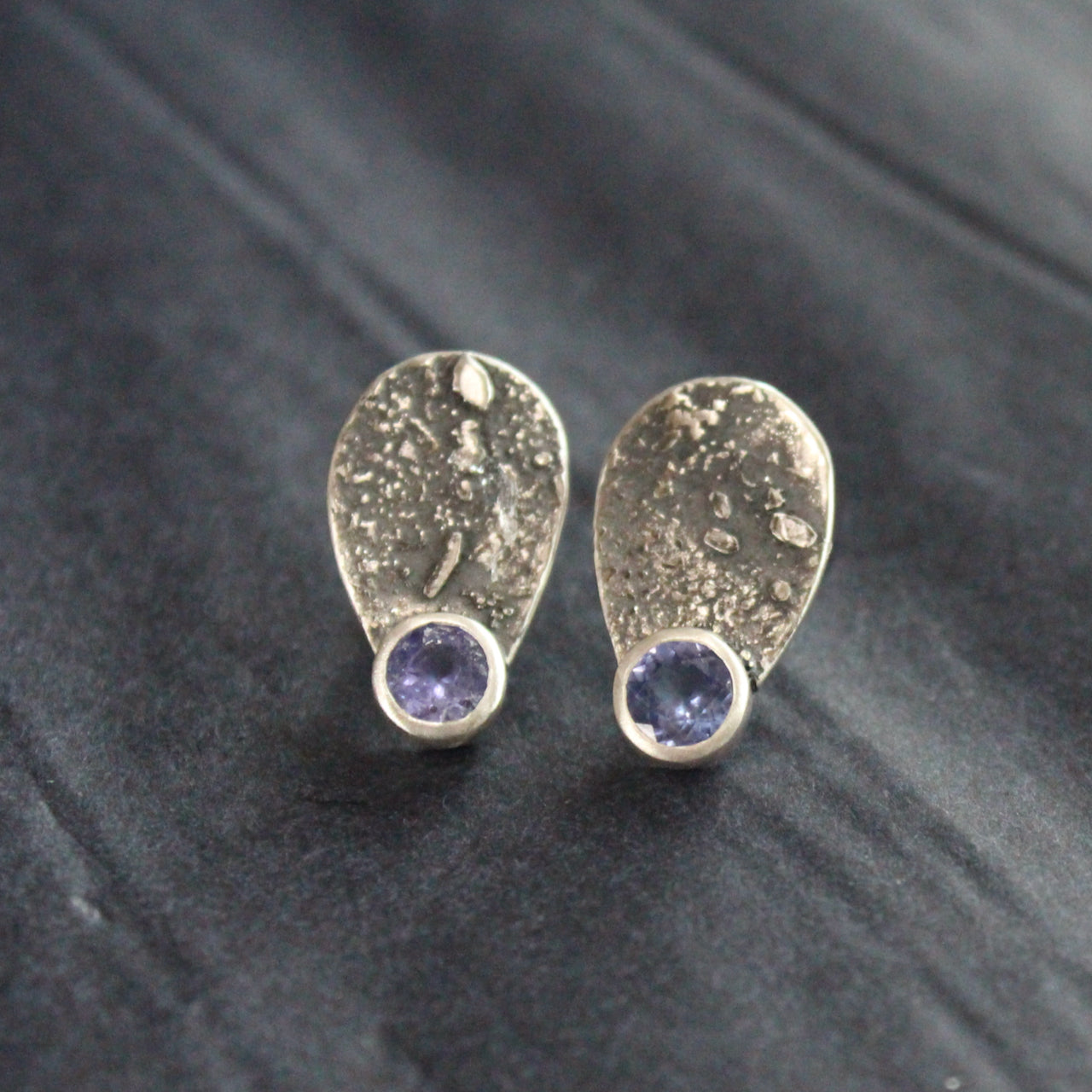 pair of Carin Lindberg textured silver earrings teardrop shape with silver encased small purple stone 