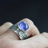 Carin Lindberg textured silver ring with a large oval blue stone and a smaller white diamond shown on a woman's finger