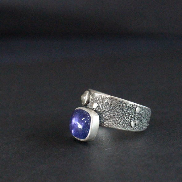 a Carin Lindberg textured silver ring with a large oval blue stone and a smaller white diamond.