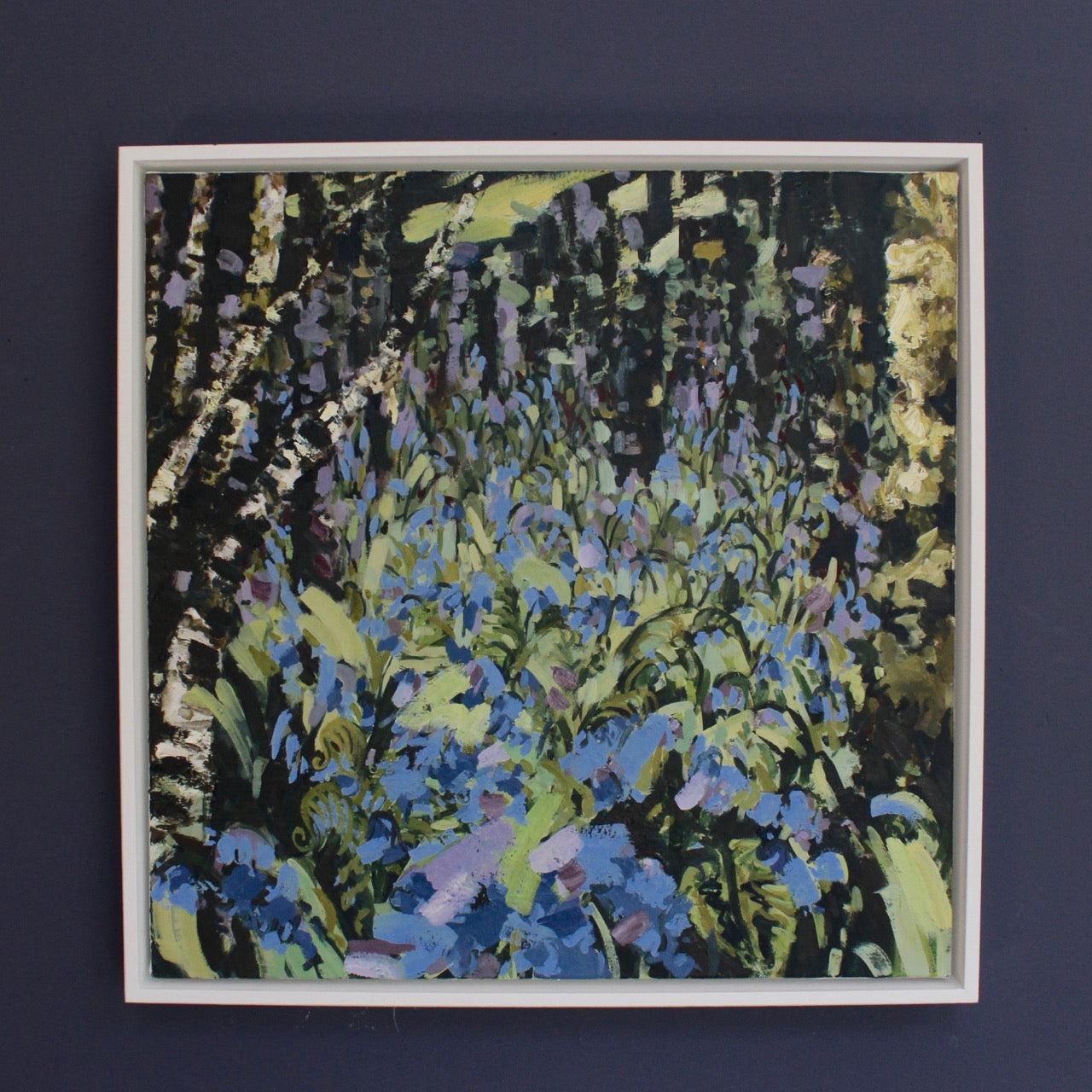 Jill Hudson, 'Bluebell Riot' an abstract painting of purple and blue bluebells in a wood - framed on a dark wall
