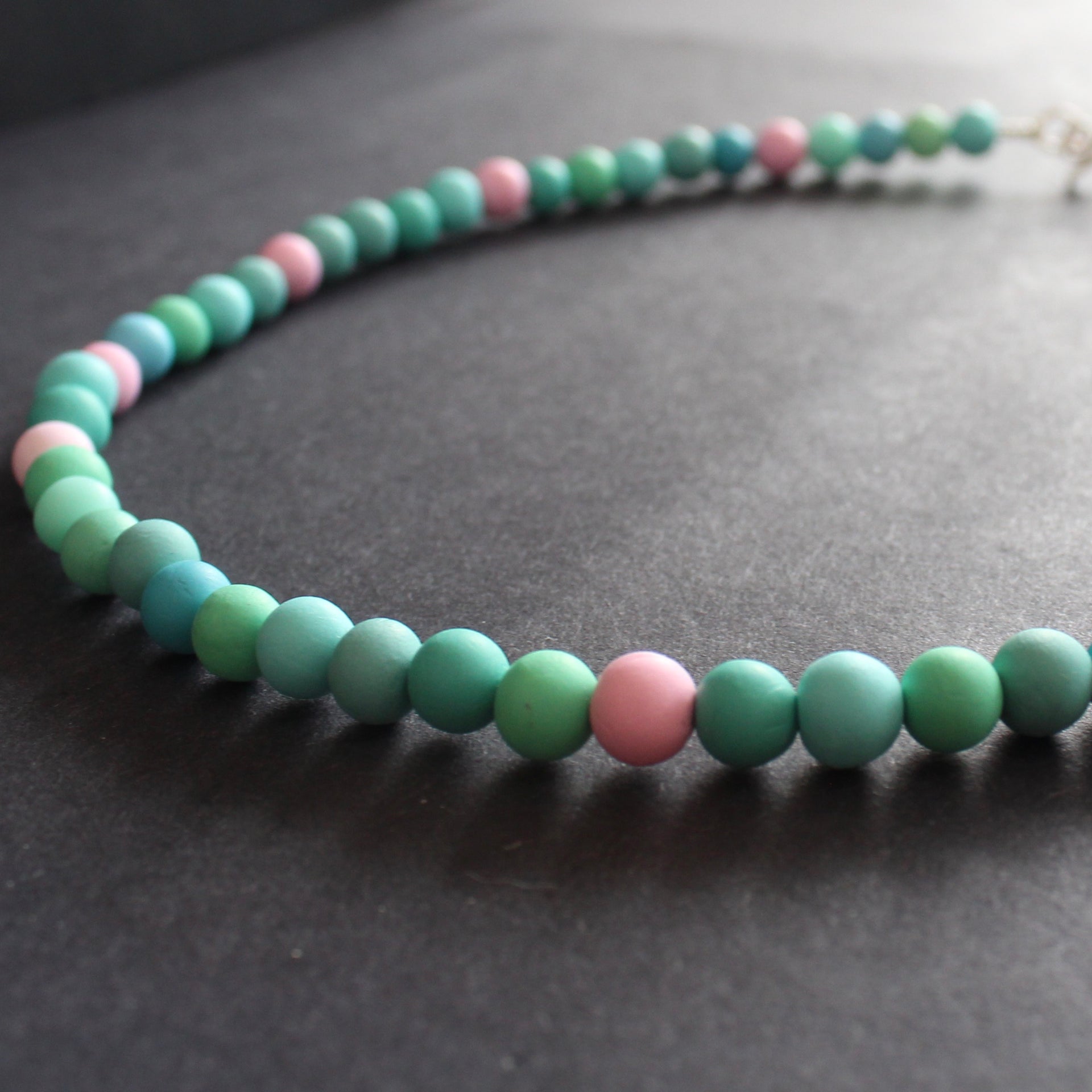 Close up of Clare Lloyd tiny bead necklace in pastels and duck egg blue