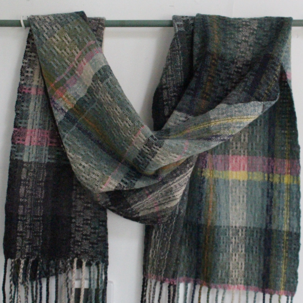 fringed handwoven scarf by UK textile artist Teresa Dunne it's in shades of green, blue, orange and pink 
