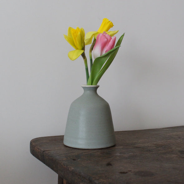 EOT ceramics bud vase in greeny grey glaze with two daffodils and a pink tulip in it 