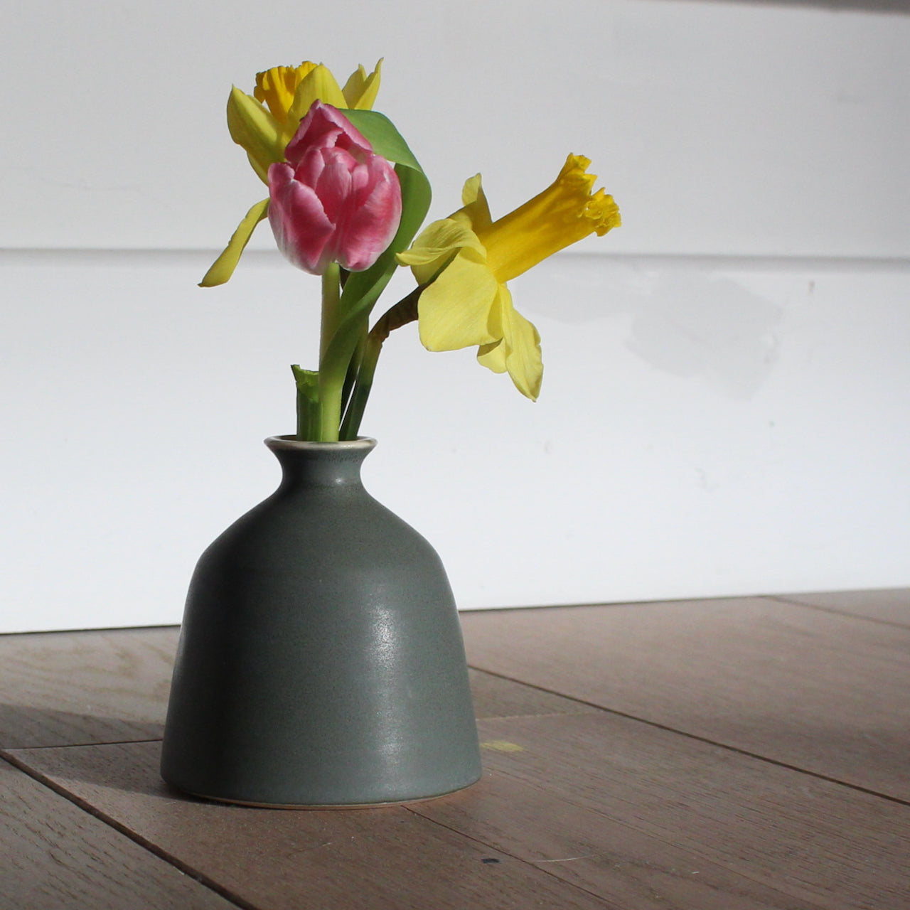 EOT ceramics bud vase in dark olive with two daffodils and a pink tulip in it