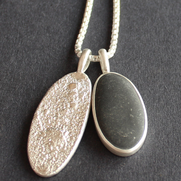 Close up of pebble and textured silver duo pendants on silver chain by Carin Lindberg