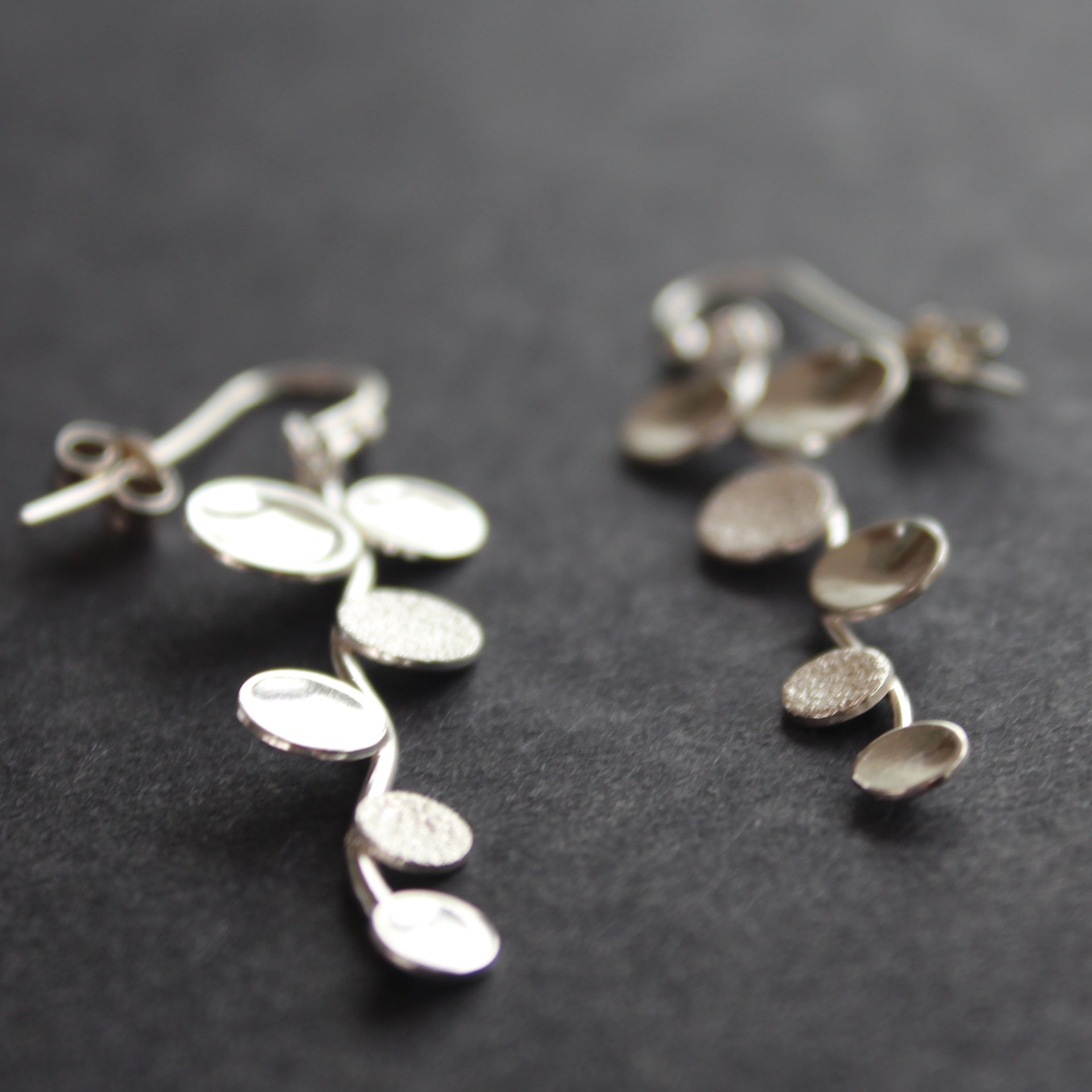 Long sliver earrings of small circles attached to central curved line made by Beverly Bartlett and shown at the Byre Gallery