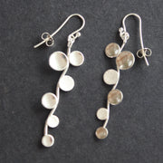Long sliver earrings of small circles attached to central curved line made by Beverly Bartlett 