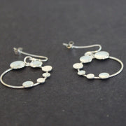 A pair of Round silver hoop earrings with small silver circles attached by Beverly Bartlett 