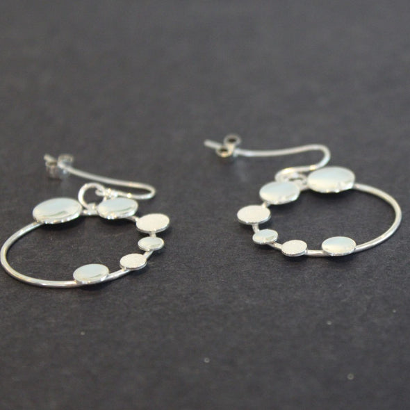 A pair of Round silver hoop earrings with small silver circles attached by Beverly Bartlett 