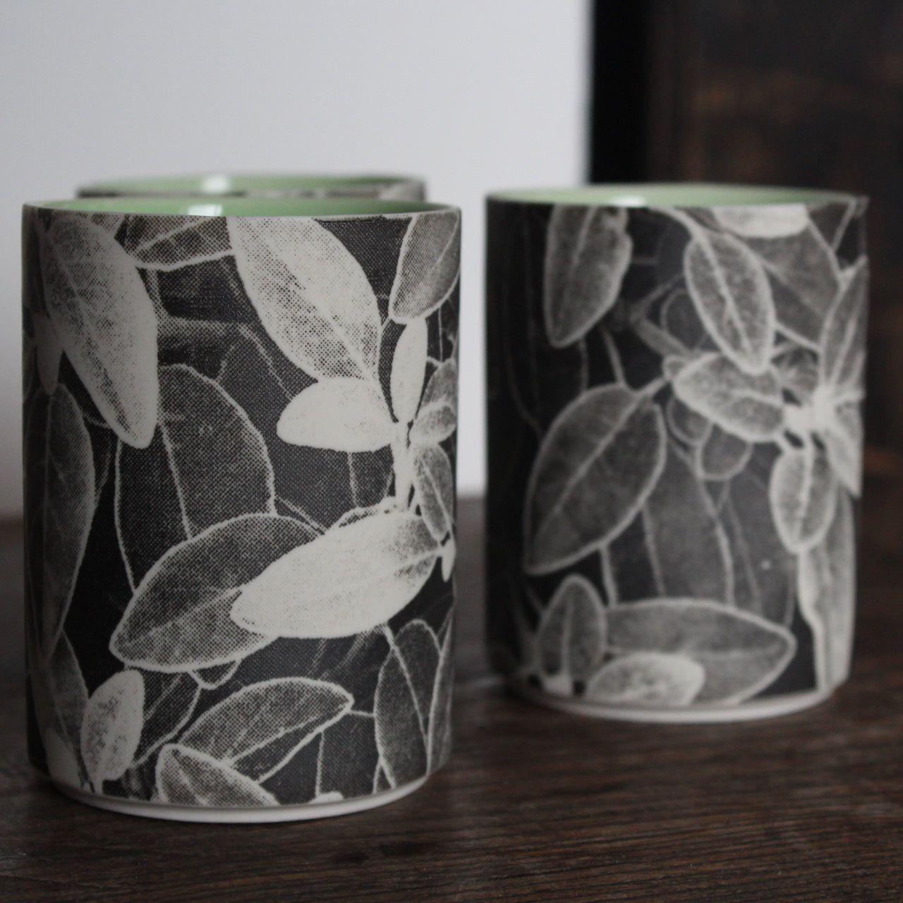 UK ceramicist Heidi Harrington trio of small ceramic beakers with a black and white photo image of leaves on the the exterior and green glazed interior