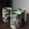 trio of small ceramic beakers by  UK ceramicist Heidi Harrington with a black and white photo image of leaves on the the exterior and green glazed interior 