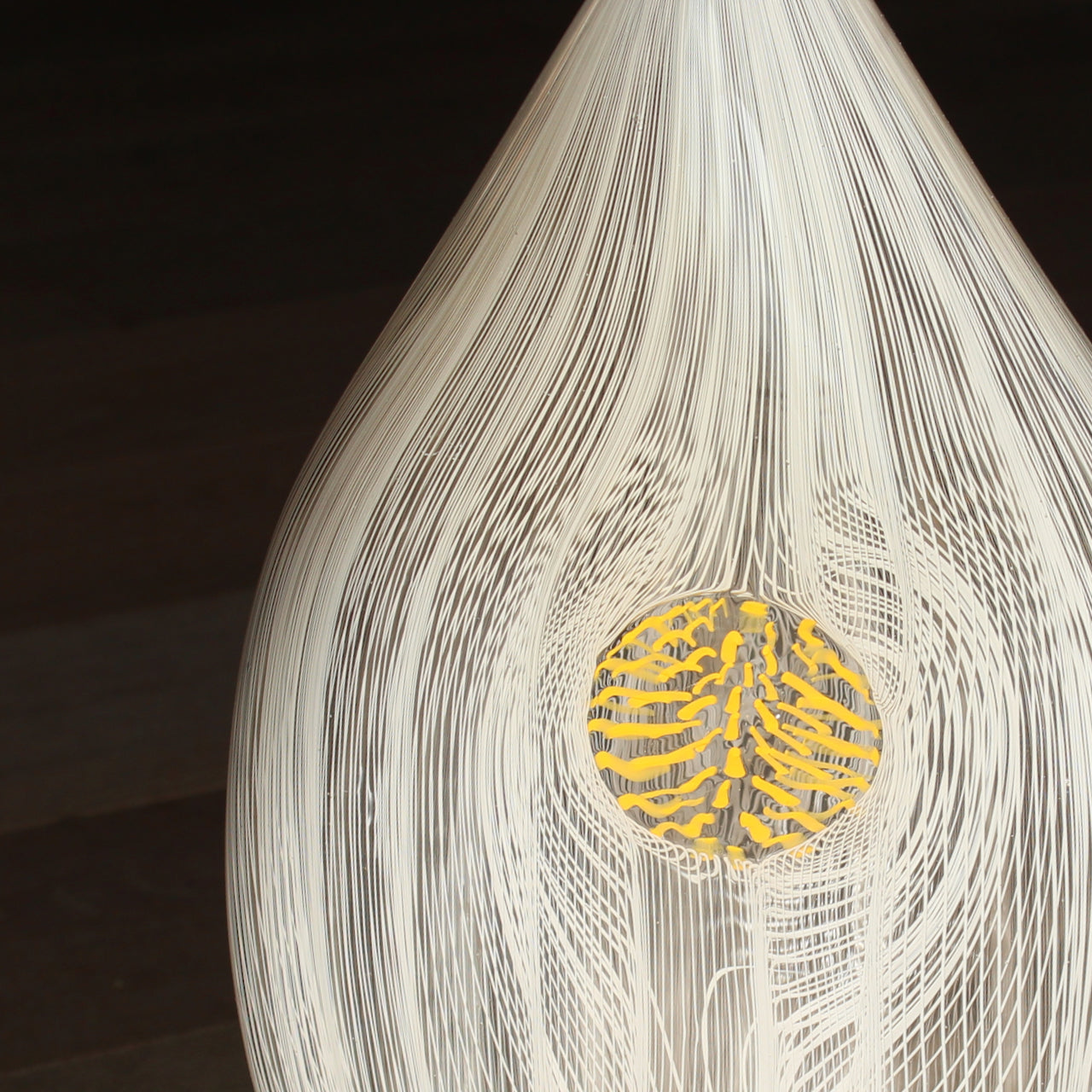 close up detail of a Benjamin Lintell tear shaped glass vase in  white and clear with central yellow detail 