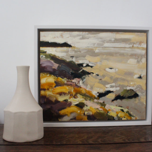 Cornwall artist Jill Hudson painting of Rame Head with yellow flowers and a sandy beach, painting is next to a white ceramic bottle made by Lucy Burley.