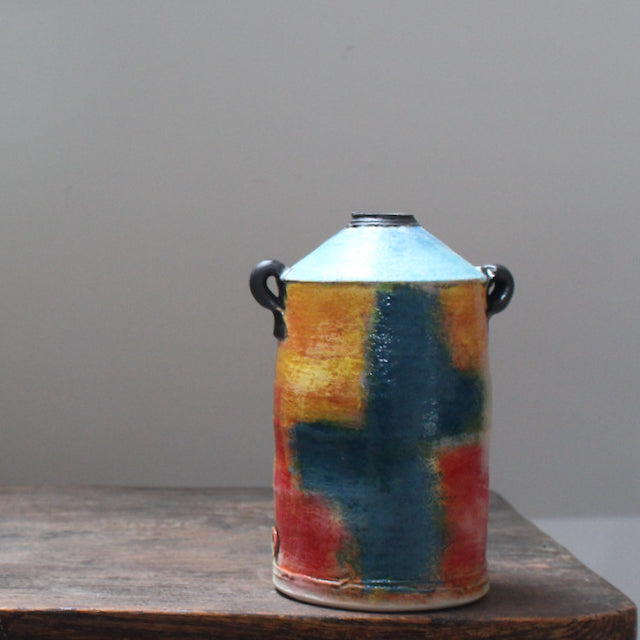 A ceramic vase with a tapered top and small lug handles by John Pollex, leading British ceramicist, multi coloured.