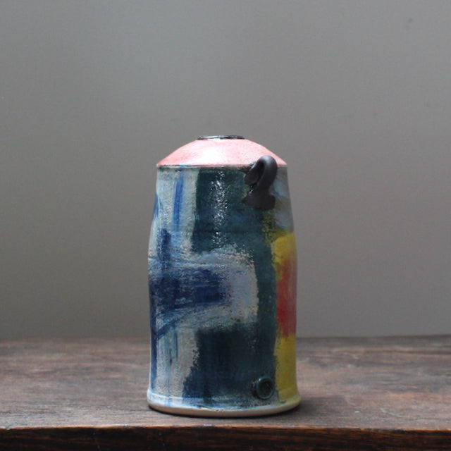 ceramic vase with a tapered top and small lug handles by John Pollex, leading British ceramicist, it is multi coloured with a pink top.