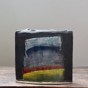 A dark ceramic vessel with rainbow style glaze by potter John Pollex.