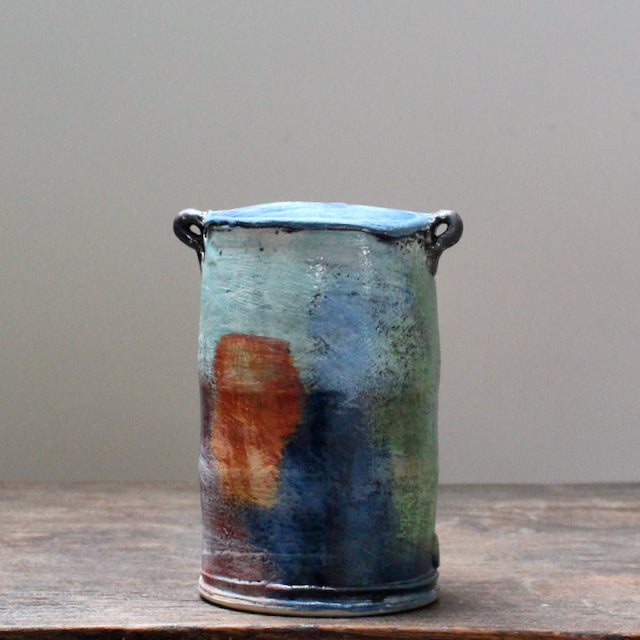 An abstract ceramic vase with a tapered top and small lug handles by John Pollex, British potter, it is multi-coloured with a blue top