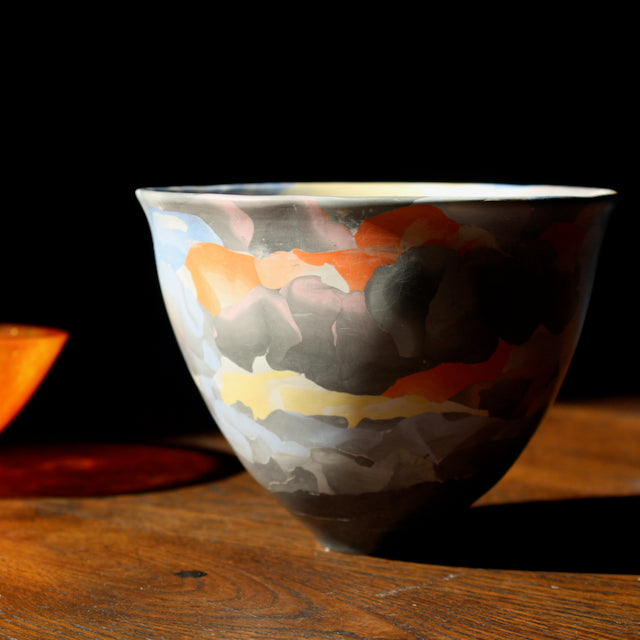 porcelain Nerikomi style bowl in dark purple, orange and yellow by ceramic artist Judy Mckenzie photographed in the sunshine.
