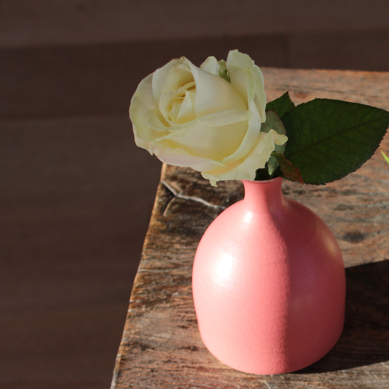 small pink ceramic posy vase with a white rose in it by UK ceramicist Lucy Burley