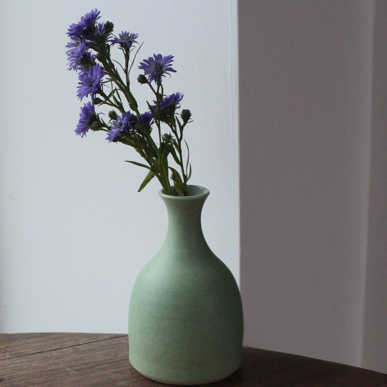 small pale green ceramic posy vase with a purple flower in it  UK ceramicist Lucy Burley