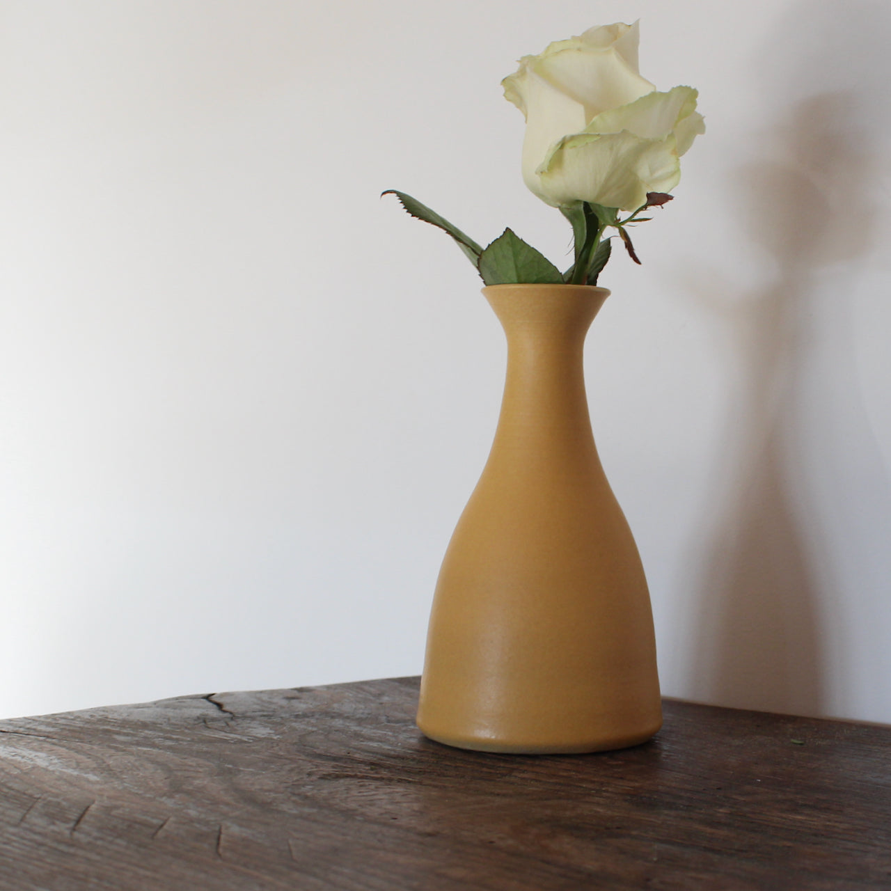 golden yellow ceramic bud  vase with white rose in it by UK ceramicist Lucy Burley