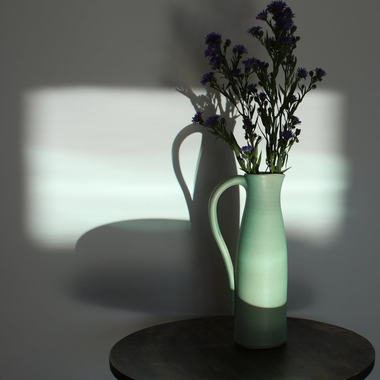 Lucy Burley duck egg blue ceramic jug with some tall purple flowers in it