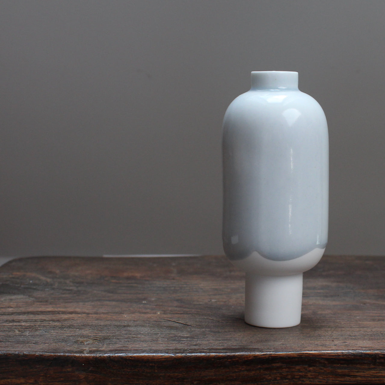 Small pale blue and white ceramic vessel on a wooden table 