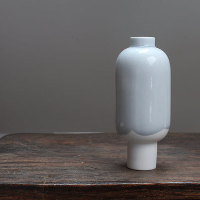 Small pale blue and white ceramic vessel on a wooden table 