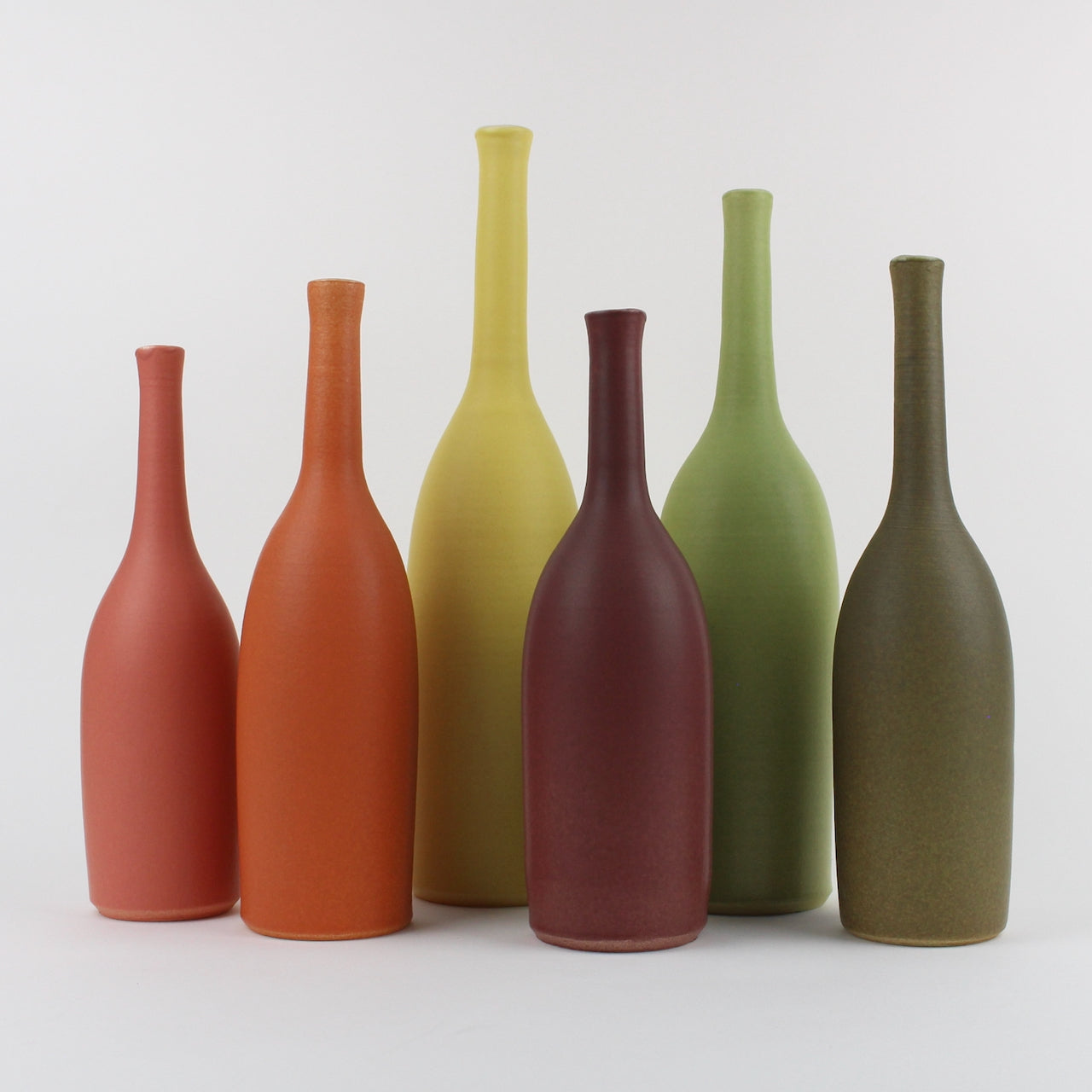 six ceramic bottles by Lucy Burley ceramicist in shades of orange, green and coral