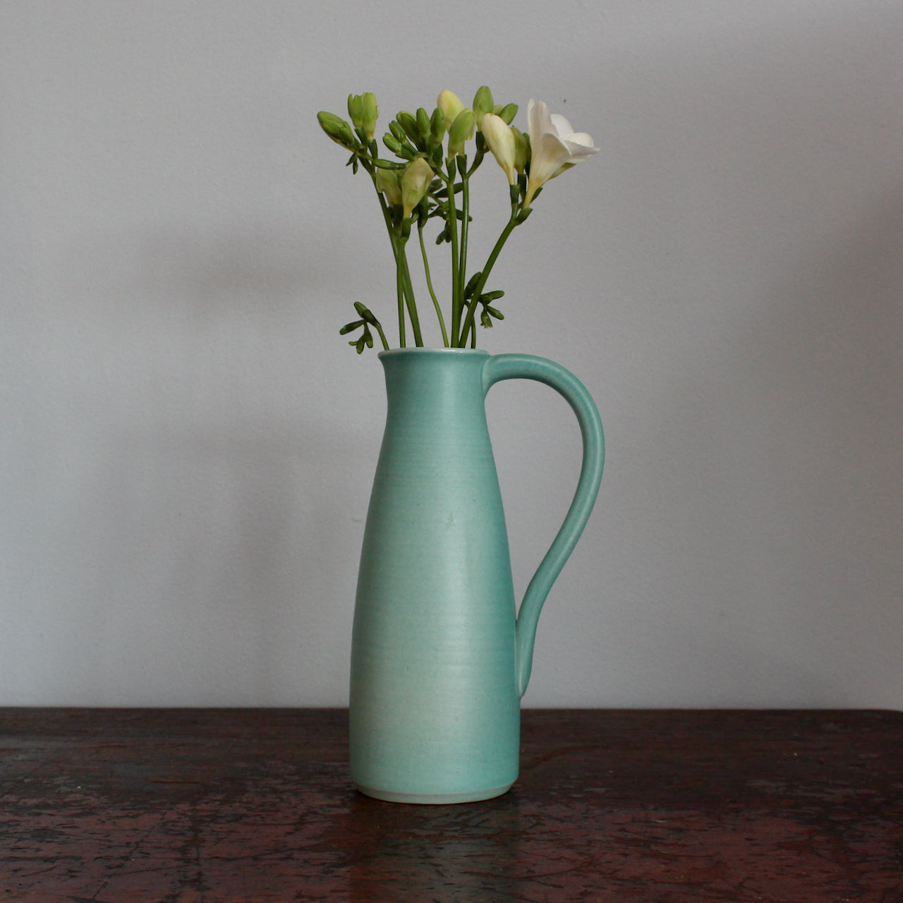 Duck egg ceramic jug with a handle by Lucy Burley on a wooden table at the Byre Gallery