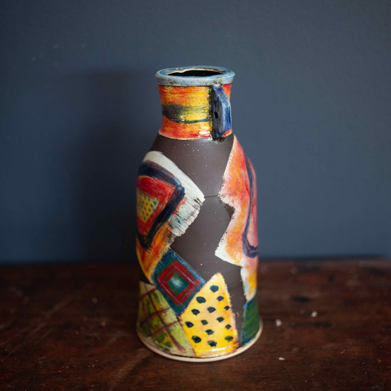 A Ceramic vase in reds, greens and blues by John Pollex