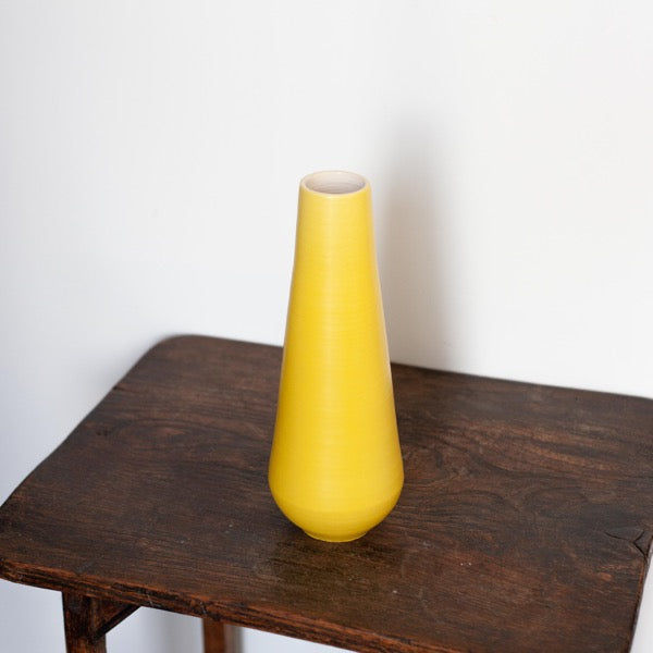 tall yellow vase by potter Lucy Burley in it and it's sitting on a wooden table.