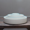 Six stacked white round bowls with a blue rim