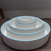 Six stacked white round bowls with a blue rim on a wooden table