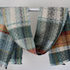 a handwoven scarf in greys, orange and yellow by Cornish textile artist Teresa Dunne.