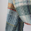 detail of a handwoven scarf in greys, orange and yellow by Cornish textile artist Teresa Dunne