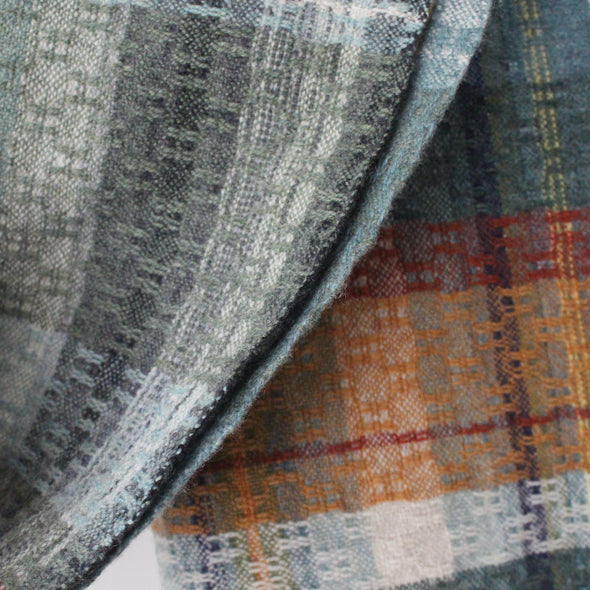close up of a handwoven scarf in greys, orange and yellow by Cornish weaver Teresa Dunne