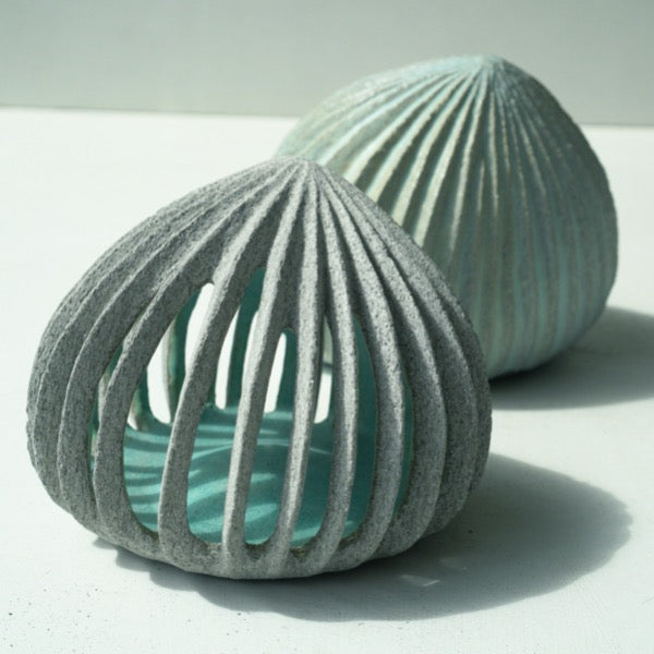 a pair of pale green carved stoneware ceramic pods shaped sculptures by Michele Bianco