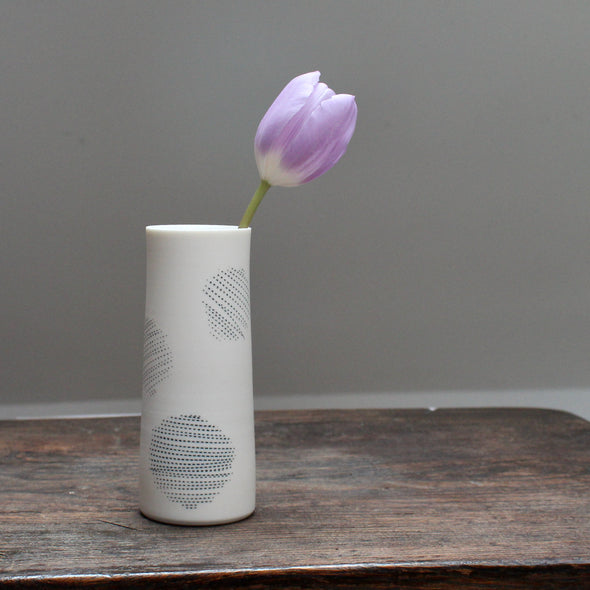 narrow ceramic white stem vase decorated with abstract circles with a lilac tulip in it 