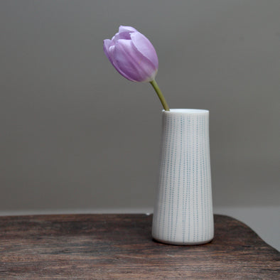 porcelain stem vase with blue vertical lines with lilac coloured tulip in it 
