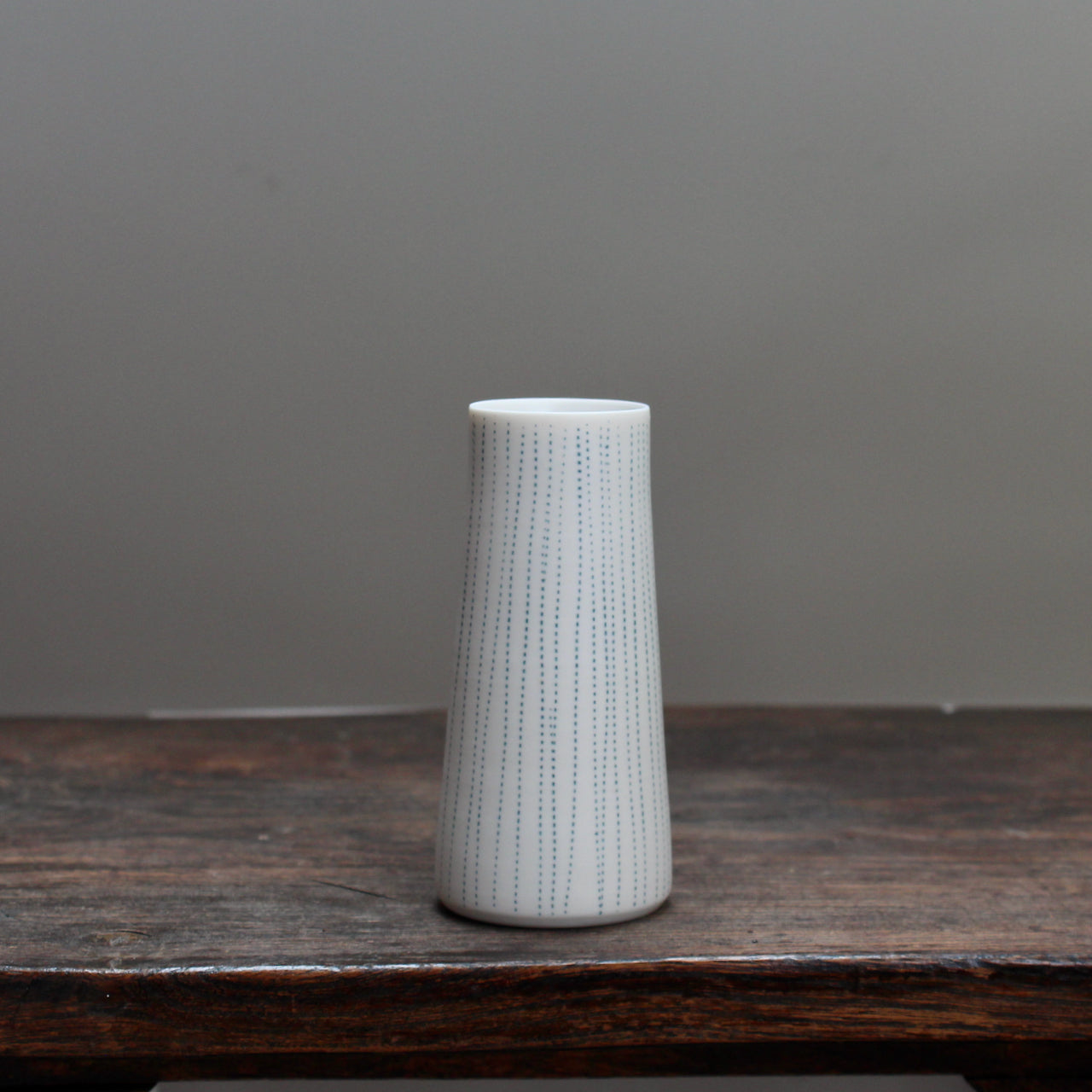 a porcelain stem vase with blue vertical lines 