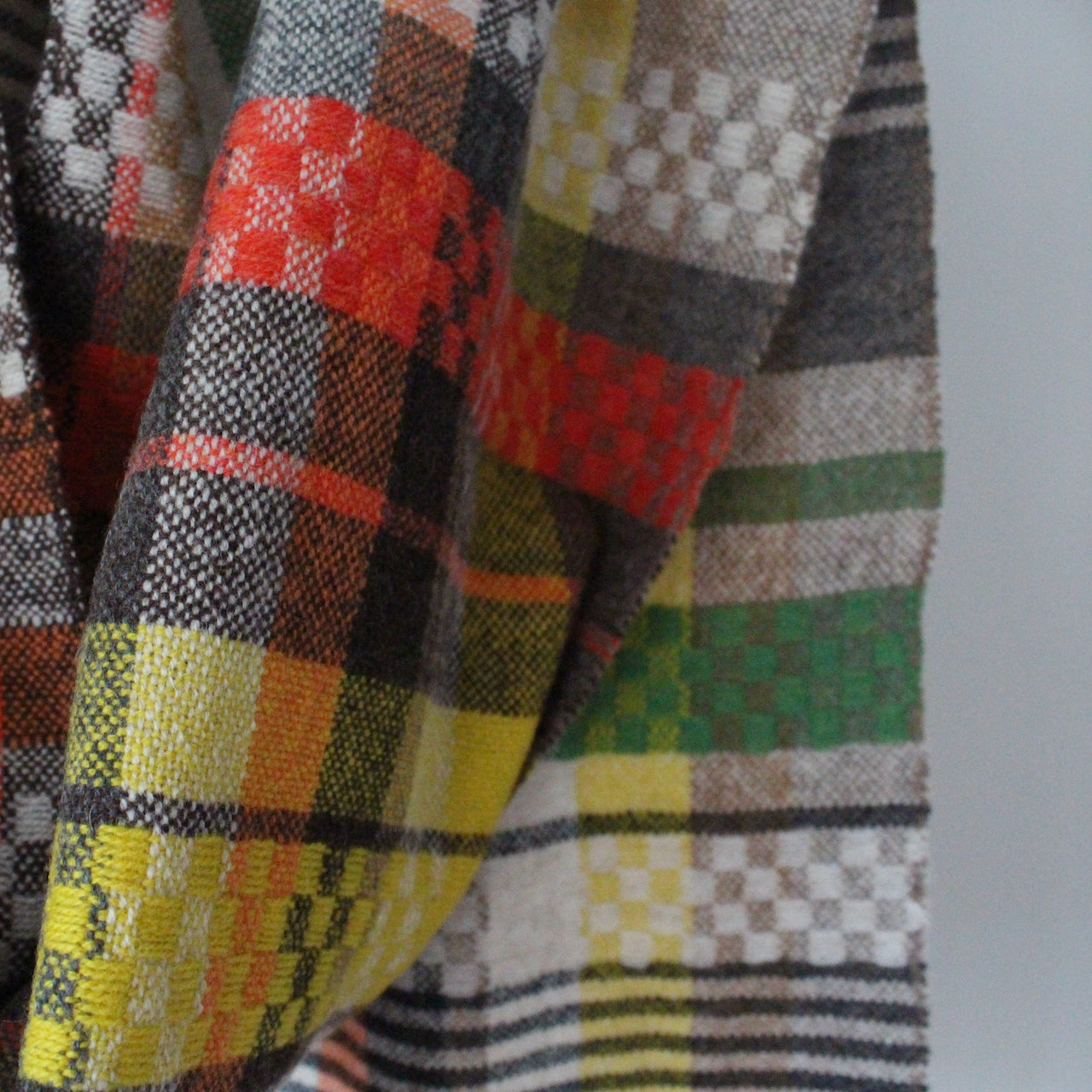 Close up of handwoven scarf in shades of yellow, green and red