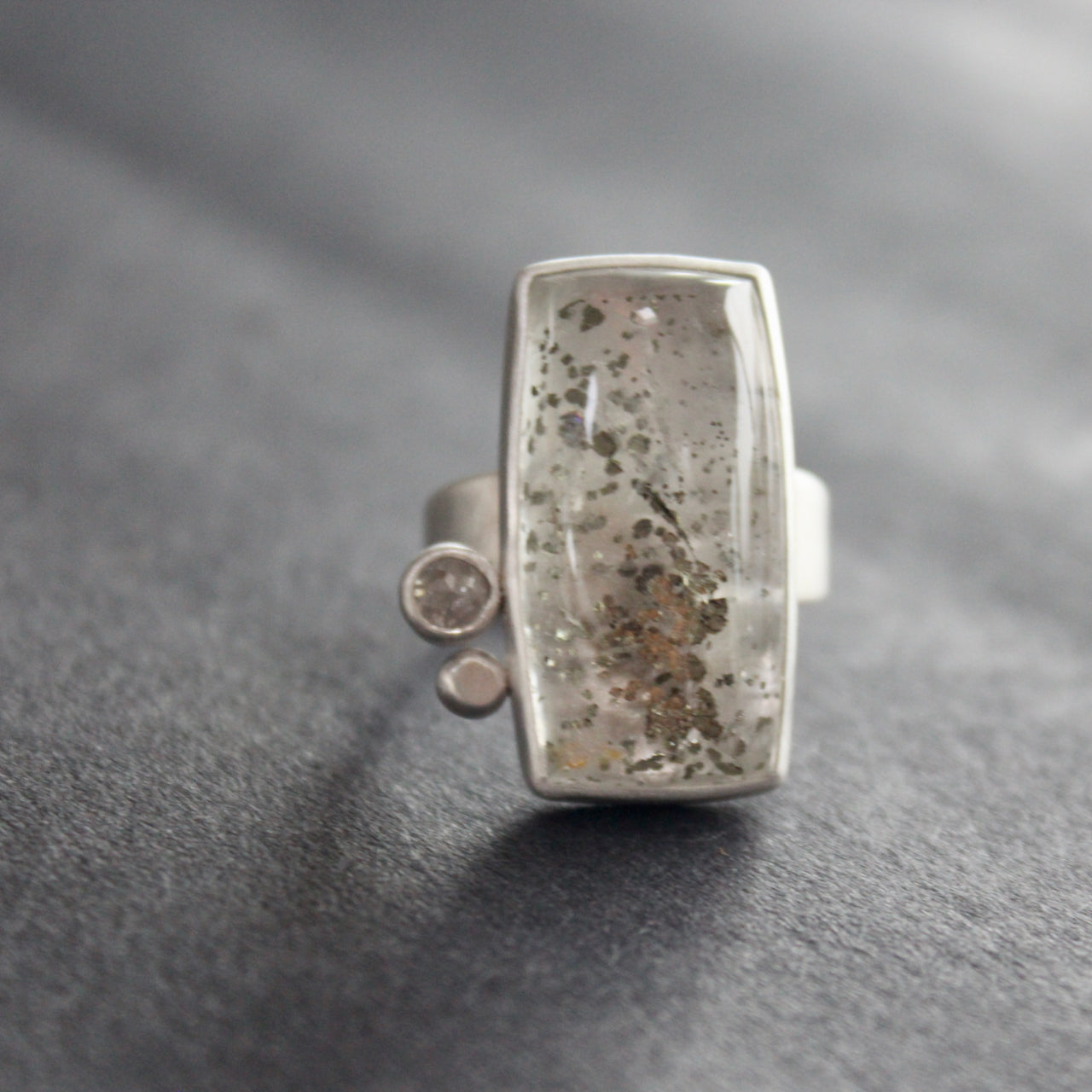Silver ring featuring large rectangular quartz stone with small diamond and small silver ball to the side