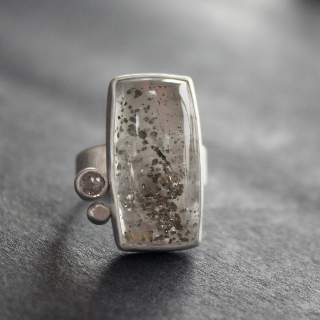 Silver ring featuring large rectangular quartz stone with small diamond and small silver ball to the side