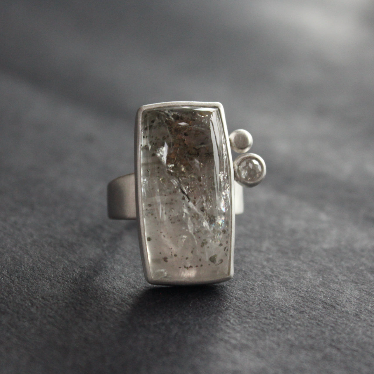 Silver ring featuring large rectangular quartz stone with small diamond and small silver ball to the side